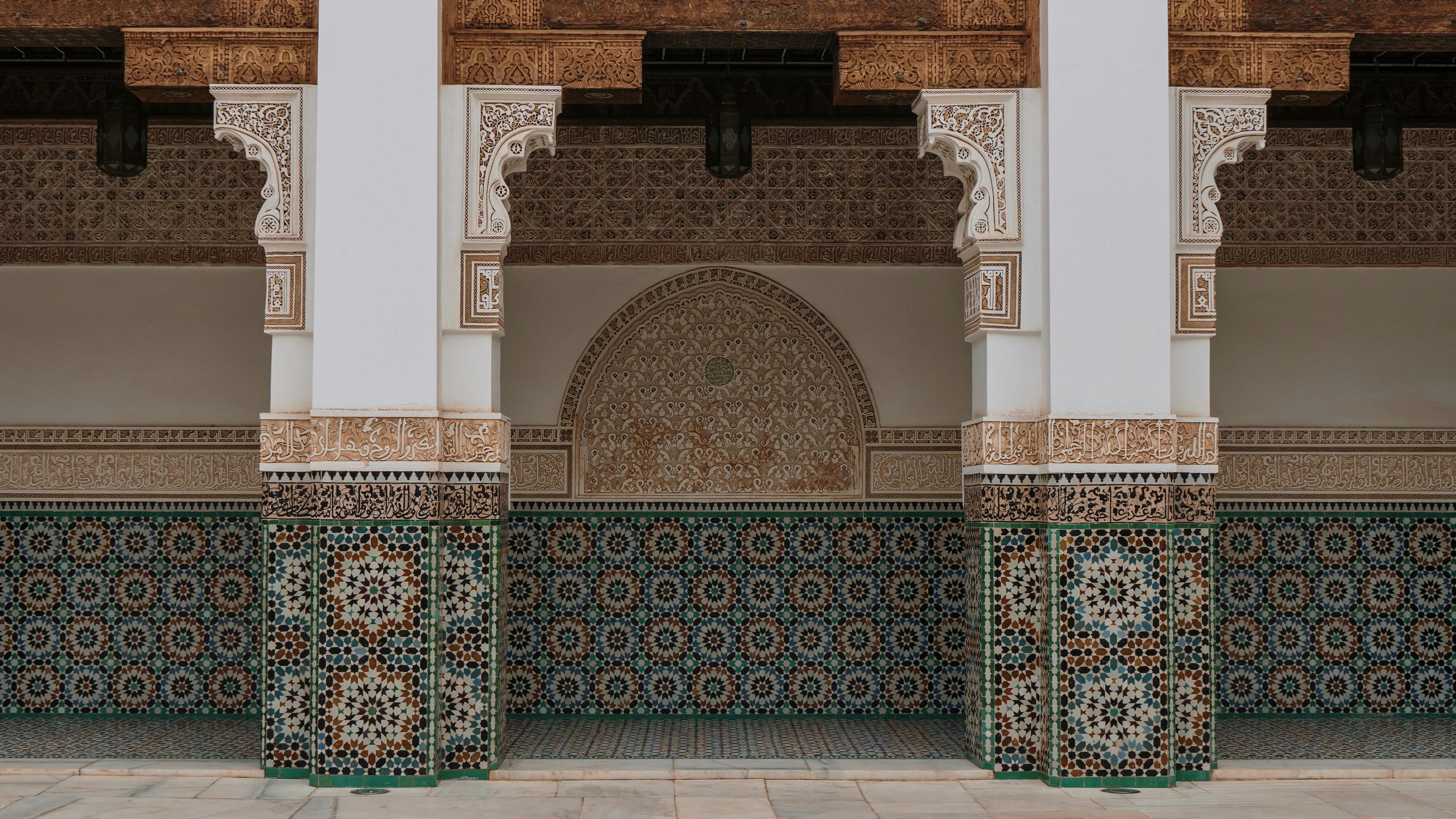 Decorative archway with intricate tile work and wooden beams in a traditional architectural style of Fez.