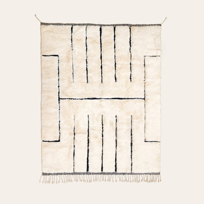 A black and white geometric patterned rug with a fringed edge.